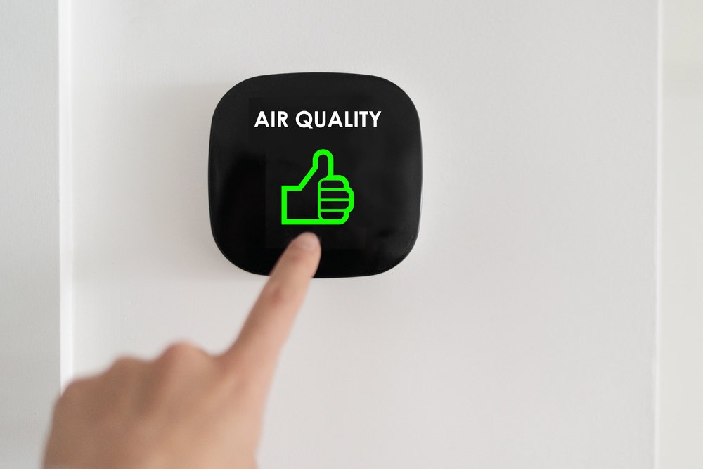Smart air quality monitor on wall showing good air quality status