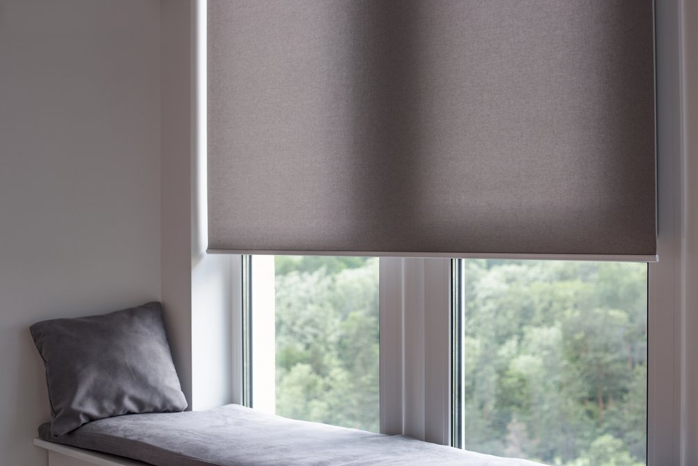 Gray motorized roller shade partially lowered in bedroom window seat