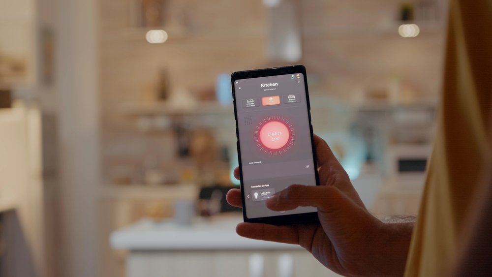 Hand holding phone with smart lighting control app in kitchen