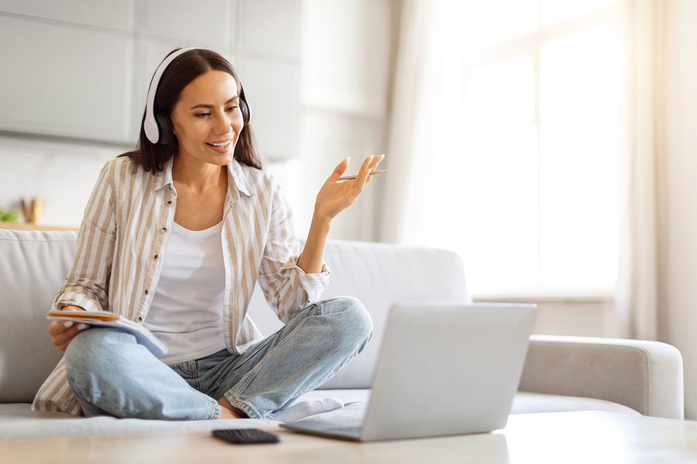 Woman on video conference call wearing headphones in home office