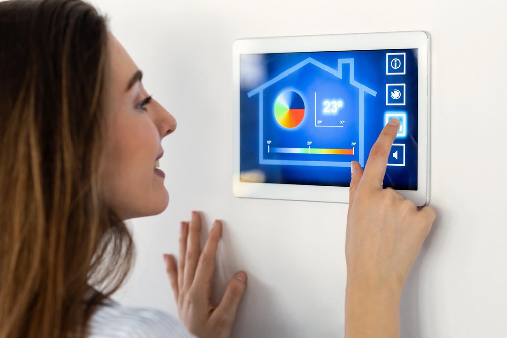 Woman adjusting temperature on wall-mounted smart home control panel